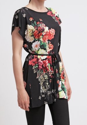 Woman wearing a black floral tunic with short sleeves and a thin black belt, paired with black leggings on a white background.