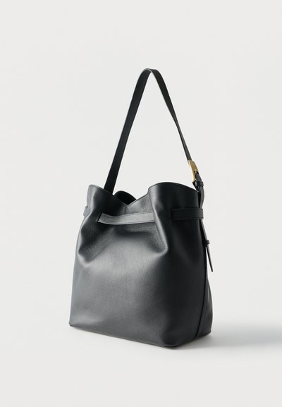 Μαύρη δερμάτινη τσάντα ώμου με ένα ρυθμιζόμενο λουράκι και χρυσή αγκράφα, μαλακή υφή, ελαφρώς χαλαρή μορφή πάνω σε λευκό φόντο.