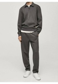 Pull gris avec col et poignets côtelés, superposé sur une base blanche. Associé à un pantalon gris assorti et des baskets blanches.