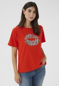 Röd bomullströja med leopardmönstrad läppdesign på framsidan, korta ärmar och en avslappnad passform mot en neutral bakgrund.