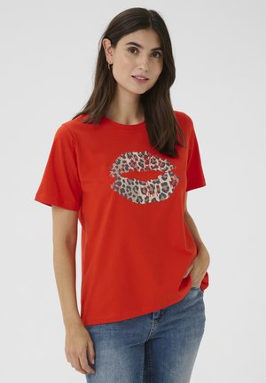 Rode katoenen t-shirt met een lipdesign in luipaardprint aan de voorkant, korte mouwen en een ontspannen pasvorm tegen een neutrale achtergrond.