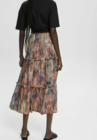 Jupe colorée à plusieurs niveaux, fabriquée en tissu léger avec un motif mélangé de teintes vives. Présente un bord froncé et un design fluide.