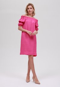 Off-shoulder rosa klänning med puffärmar och textil med struktur, knälång design, tillsammans med nude högklackade skor.