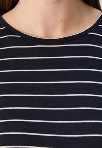 Tumesinine T-särk valgete horisontaalsete triipudega, ümar kaelus ja sile puuvillane kangas. Ilma nähtavate logode või graafikateta.