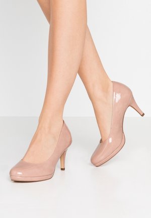 Chaussures à talons hauts en cuir verni nude avec une finition lisse, un bout rond, des côtés dégagés et un talon fin.