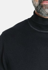 Suéter negro de cuello alto con textura acanalada, que presenta un diseño ajustado. Liso, sin patrones ni adornos.