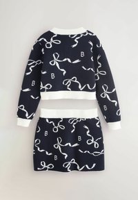 Set di maglione e gonna in maglia blu navy con stampa a nastro bianco e leggere coste sui polsini e orli. Il maglione presenta la lettera "B" nel motivo.