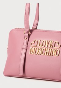 Roza vrečka iz umetnega usnja z zlatim logotipom "LOVE MOSCHINO", dvojni ročaji, zapiranje na zadrgo in gladka tekstura.