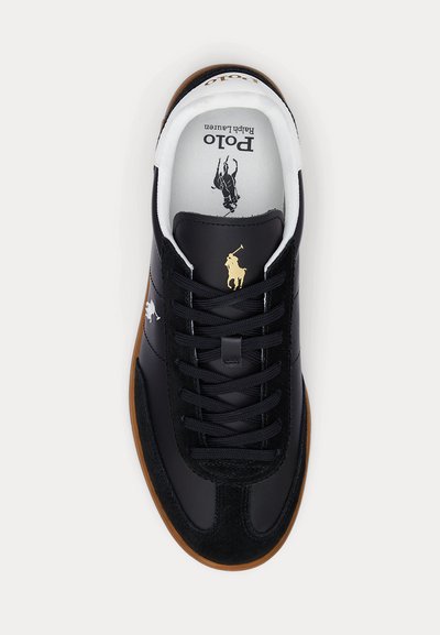 Zwarte leren sneaker met bruine zool, zwarte veters en gouden Polo Ralph Lauren paardenlogo op de tong en zijkant.
