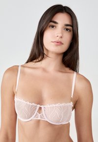 Hellrosa Spitzen-BH mit halbtransparentem Stoff, floraler Stickerei, gewelltem Rand und goldenen Beschlägen. Verstellbare Träger für eine optimale Passform.