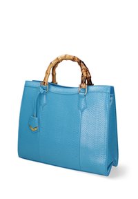 Borsa a tracolla in pelle blu con texture, manico in bambù, dettagli in ottone dorato e un piccolo tag decorativo attaccato.