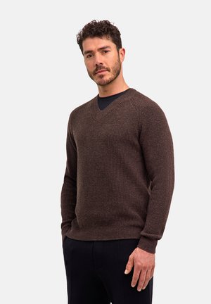 Brązowy sweter wykonany na drutach z dekoltem w kształcie V, teksturowana tkanina, ściągacze przy mankietach i u dołu. Nosi się go na czarnej koszuli, w zestawieniu z ciemnymi spodniami.