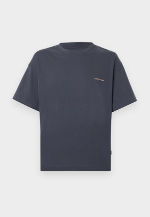 T-shirt gris foncé à manches courtes avec col rond et petit texte orange sur le haut du côté gauche de la poitrine, présenté sur un fond clair uni.
