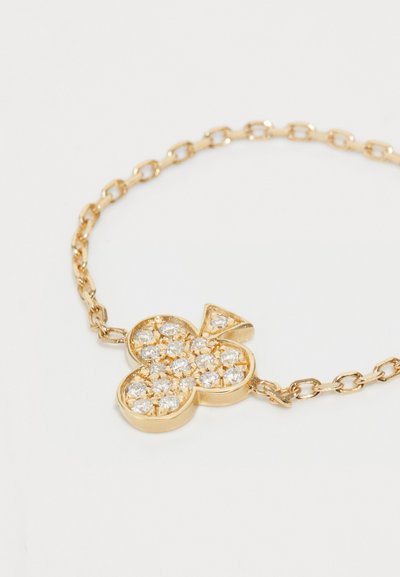 Gold chain bracelet featuring a clover-shaped pendant, adorned with clear rhinestones, showcasing a polished finish and intricate detailing.