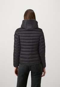 Svart boblejakke med hette, kviltet design og en litt figursydd fasong. Materialet ser glatt og lett ut.