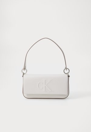 Borsa in pelle bianca con logo "CK" in rilievo, forma cilindrica, design snello, bordi scuri a contrasto e un manico singolo in cima con finiture in argento.