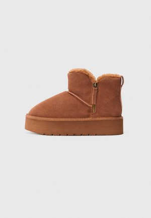 Stivaletto in suede marrone con suola platform, zip laterale e pelliccia visibile sul bordo superiore.
