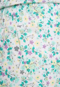 Tissu floral avec de petites fleurs jaunes, violettes et turquoise sur un fond blanc, doté d'une taille élastique et de poches latérales.
