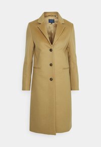 Cappotto beige di lunghezza al ginocchio realizzato in misto lana, con rever a punta, tre bottoni neri e due tasche laterali. Texture liscia.