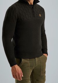 Pull tricoté vert foncé avec une demi-fermeture éclair, présentant un motif en losange texturé sur la partie supérieure et des bords-côtes aux poignets et à l'ourlet.