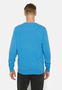 Pulover albastru din material moale, cu mâneci lungi, manșete și tiv cusute în dantelă, având un design simplu și guler rotund.