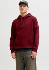 Bordeaux huppari, jossa on kengurupocket, nyörihuppu, ribattuja hihansuita ja hillitty logo yksityiskohtana rinnassa. Yhdistetty haalistuneisiin farkkuihin.