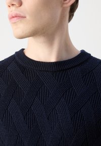 Maglione lavorato a maglia blu navy con un motivo intrecciato spesso e testurizzato e colletto a coste, che mette in mostra dettagli intricati e un design aderente.