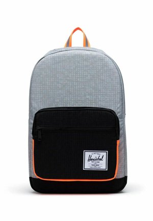 Sac à dos gris et noir avec une poche zippée à l’avant soulignée d’orange et une étiquette rectangulaire blanche de la marque Herschel sur la poche.