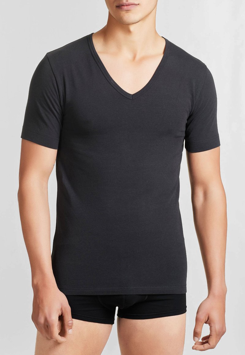 T-shirt nera a collo a V con maniche corte, realizzata in tessuto liscio, caratterizzata da un design aderente che si adatta al corpo.
