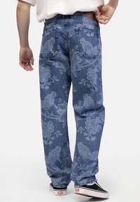 Light blue denim jeans with a floral pattern in light blue. Straight-leg fit with back pockets and a subtle faded texture.