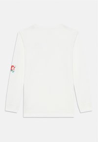 Pitkähihaisessa valkoisessa t-paidassa on sileä pinta. Vasemmassa hihassa on brodeerattu kuvio punaisissa, sinisissä ja vihreissä sävyissä.