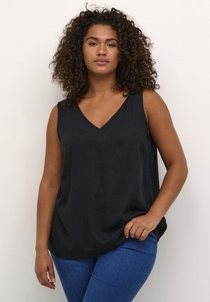 Top sans manches noir avec un décolleté en V, fabriqué en matériau doux, présentant une coupe décontractée et des fentes latérales discrètes. Associé à un jean bleu.