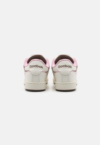 Sneakers Reebok con tomaia in pelle bianca, dettagli in rosa pallido e colletto in suede marrone. Presentano il logo sul tallone e una suola in gomma testurizzata.