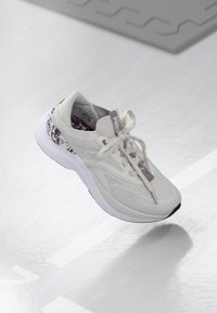 Baskets blanches avec un dessus en tricot texturé, accents violets et semelle extérieure en caoutchouc solide. Comprend des lacets et un design de talon à motif.