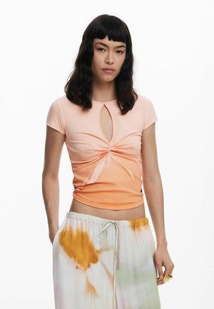 Camisa de manga corta en un degradado de melocotón claro a naranja, con un detalle de ojo de cerradura en el escote. Tejido suave con una silueta ajustada.