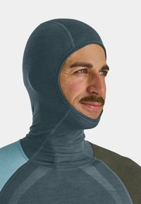 Balaclava with a fitted shape, made of soft, dark blue fabric. Features stitched seams and a contrasting light blue shoulder accent.
