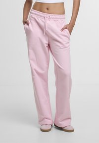 Lyserøde sweatpants med snor i taljen, elastiske manchetter og sidelommer, lavet af blødt stof, med en løs pasform og glat tekstur.