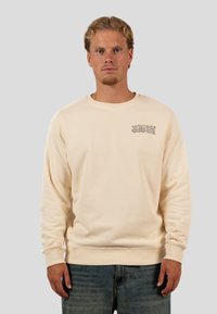 Felpa beige chiaro con polsini e orlo a coste, con un piccolo logo stampato "WRONG FRIENDS" sul petto. Materiale morbido in misto cotone.