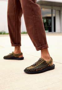 Oliven grønne sandaler med flettet stof, gummisål og sporty design. Åben bagside med justerbare snørebånd for en bedre pasform.