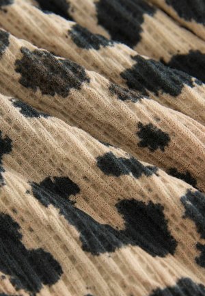 T OAuth fabric cu o textură ondulată, având un fundal bej și pete negre neregulate care creează un model contrastant.