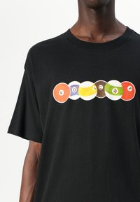 Black cotton t-shirt featuring a front graphic of colored circular shapes with the text "VOLCOM" integrated into the design.