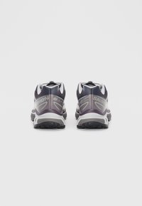 Schwarze und lila Trailrunning-Schuhe mit grauen Akzenten, ausgestattet mit einer strukturierten Sohle und einem sicheren Schnürsystem. Branding an der Seite.