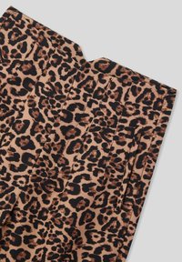 Tessuto a stampa leopardo con pences verticali cucite e una tasca laterale stretta su uno sfondo grigio chiaro.