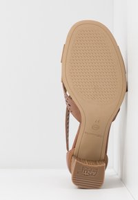 Sandale avec semelle beige et talon bloc montrant le motif de la semelle, taille 37, et étiquette antidérapante sur fond blanc en coin.