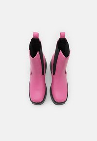 Botas de cuero rosa hasta el tobillo con lados elásticos negros, puntera cuadrada y una pestaña en el talón. Suela de goma negra para agarre y durabilidad.