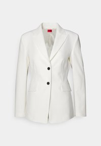 Biała, dopasowana marynarka z wyciętymi klapami, dwoma czarnymi guzikami i przednimi kieszeniami. Gładka faktura z wzorzystą podszewką.