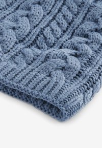 Coperta lavorata a maglia in morbido filato blu medio, caratterizzata da un motivo a treccia testurizzato con trecce sollevate e bordi a coste.