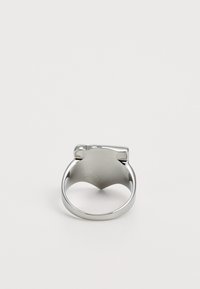 Silver ring with a smooth, polished surface, featuring a unique bow-shaped accent on top and a rounded band. The interior is textured.