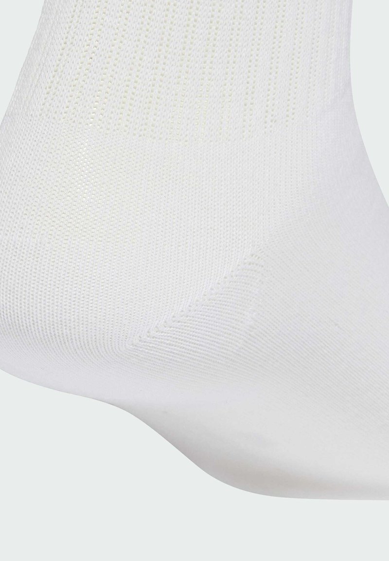 Vita bomullsstrumpor med ribbad textur, utrustade med förstärkt häl och tå. Mjukt, lätt design. Strumpan täcker ankeln.