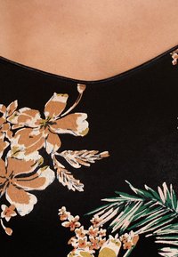 Černá látka s velkými květinovými vzory v béžových a zelených tónech, doplněná o listové akcenty a hladkou texturou. Design s výstřihem do V.